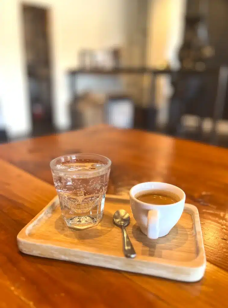 a Cup of water with a cup of espresso on a little wood plate
