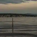 View of Lake Washington from Magnuson Park with sun setting in the background over a house filled shoreline.