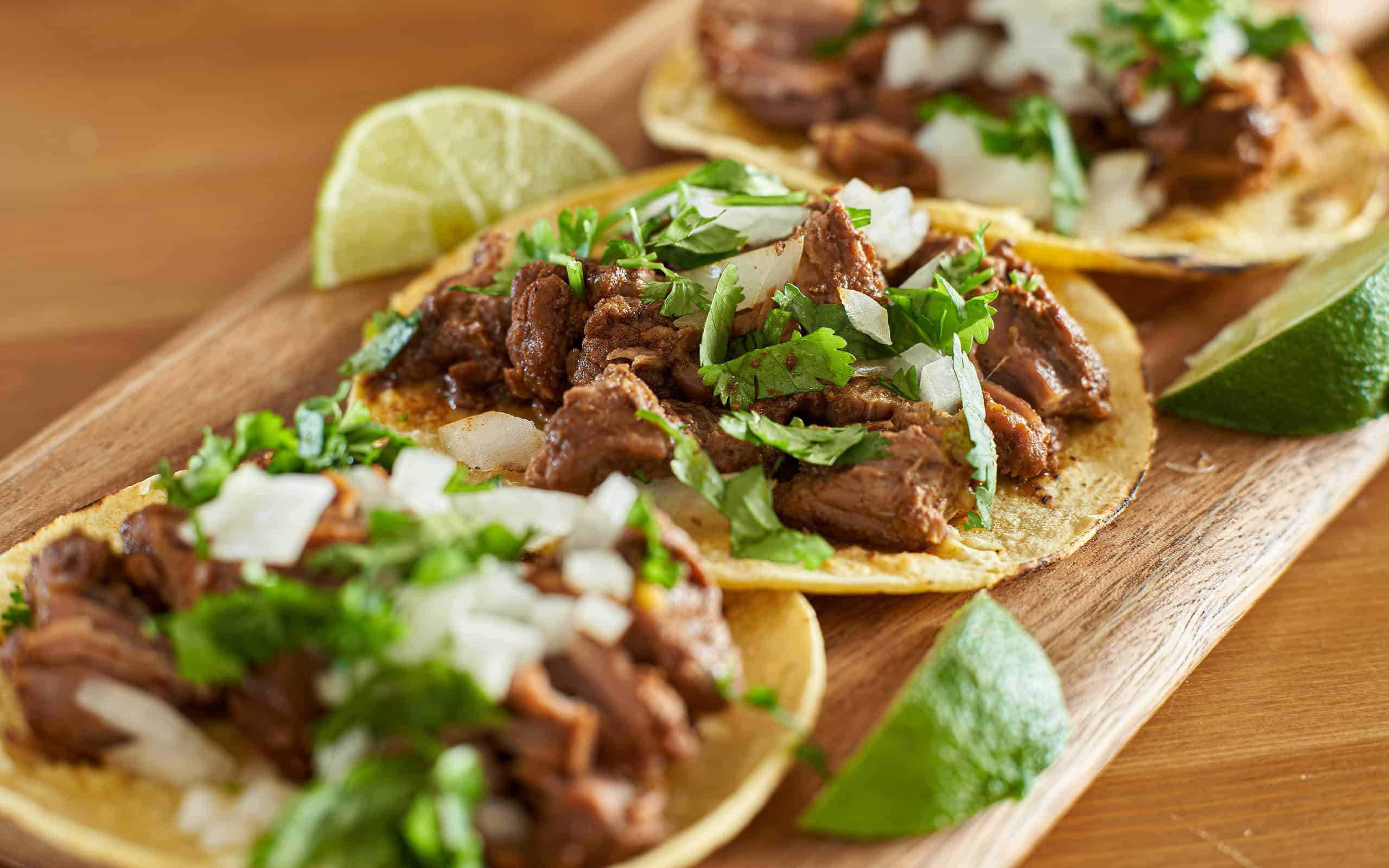three carne asada mexican street tacos in corn tortilla with lime