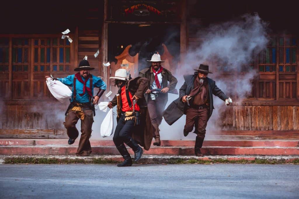Cowboys group showing action success bank rob with fighting gun and a lot of money from rob the bank with white smoke vintage style background